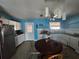 Bright kitchen boasts blue walls, white cabinetry, stainless fridge, and a circular wooden dining table at 303 60Th W Ave, Bradenton, FL 34207