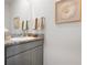 Clean half bathroom featuring a gray cabinet, a granite countertop and a decorative flower wall art at 3677 Turning Tides Ter, Bradenton, FL 34208