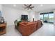 Spacious living room featuring a leather sofa, ceiling fan, and sliding glass doors to a patio at 3677 Turning Tides Ter, Bradenton, FL 34208