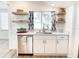 Kitchen featuring floating shelves, white cabinets, stainless steel appliances, and view to living area at 4 Braden Castle Dr, Bradenton, FL 34208
