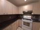 Kitchen featuring light wood cabinets, dark countertops, white appliances, and tile flooring at 4031 Iola Dr, Sarasota, FL 34231