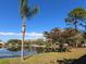 A serene backyard with a pond and lush trees under a sunny, blue sky at 4627 Breezy Pines Blvd, Sarasota, FL 34232