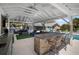 Covered outdoor kitchen with a stone bar, seating, and outdoor living area with pool views at 4711 Placid Cir, Sarasota, FL 34231