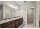 Bathroom featuring double sinks, granite countertops, dark wood cabinets, and access to a walk-in closet at 5085 Ivory Stone Dr, Wimauma, FL 33598
