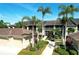 Condominium exterior featuring lush landscaping, palm trees and attached garages under a bright blue sunny sky at 5211 Mahogany Run # 113, Sarasota, FL 34241