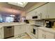 Bright kitchen with white cabinets, appliances, tile flooring, and a view into the living area at 5211 Mahogany Run # 113, Sarasota, FL 34241