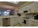 Bright kitchen with white cabinets, appliances, tile flooring, and a view into the living area at 5211 Mahogany Run # 113, Sarasota, FL 34241