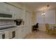 Well-lit kitchen with white appliances and cabinets plus tile floors and a small adjacent dining area at 5211 Mahogany Run # 113, Sarasota, FL 34241