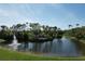 Scenic aerial of landscaped pond with fountains and lush green spaces and a community sign at 5211 Mahogany Run # 113, Sarasota, FL 34241