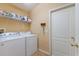 Bright laundry room with white washer and dryer, overhead shelving, and a convenient access door at 5227 Lansdowne Way, Palmetto, FL 34221