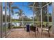 Cozy screened patio featuring comfortable seating and serene water view with swaying palm trees at 5227 Lansdowne Way, Palmetto, FL 34221