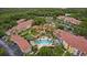 Aerial view of an apartment complex with a pool, surrounded by lush greenery, palm trees, and parking areas at 5450 Bentgrass Dr # 5-301, Sarasota, FL 34235