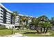 Exterior view of the condo building, surrounded by lush green lawns and palm trees at 5855 Midnight Pass Rd # 303, Sarasota, FL 34242