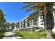 Exterior view of a curved white condo building, showcasing well-manicured lawns and trees at 5855 Midnight Pass Rd # 303, Sarasota, FL 34242