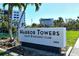 Exterior signage for Harbor Towers Yacht & Racquet Club with lush greenery and waterfall feature nearby at 5855 Midnight Pass Rd # 303, Sarasota, FL 34242