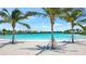 A sandy beach with palm trees and blue water at 6027 White Mangrove Ln, Bradenton, FL 34210