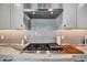 Close-up of a modern gas cooktop with sleek range hood and tile backsplash at 6027 White Mangrove Ln, Bradenton, FL 34210