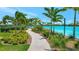 A sidewalk with palm trees and green grass leading to a turquoise lake at 6027 White Mangrove Ln, Bradenton, FL 34210