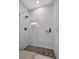 A modern shower featuring mosaic tile flooring, a glass enclosure, and white tiled walls at 6027 White Mangrove Ln, Bradenton, FL 34210