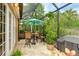 Screened-in patio features travertine tile flooring, comfortable seating, and a tropical umbrella at 6103 Aviary Ct, Bradenton, FL 34203