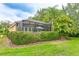 A landscaped backyard features a screened in patio with a brown metal roof over the structure at 6103 Aviary Ct, Bradenton, FL 34203