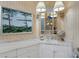 Bathroom vanity with marble countertops, white cabinets, and a decorative mirror under elegant lighting at 612 Weston Pointe Ct, Longboat Key, FL 34228