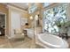 Light and bright bathroom featuring a vanity, soaking tub, large windows, and a decorative armchair at 612 Weston Pointe Ct, Longboat Key, FL 34228