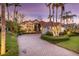 Beautiful home with red tiled roof, lush landscaping and a circular driveway at dusk at 612 Weston Pointe Ct, Longboat Key, FL 34228