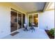 Covered outdoor patio area features neutral toned patio, sliding glass doors, table with chairs, and manicured plants at 6642 Cheswick St, Sarasota, FL 34243