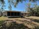 Back view of home featuring a screen enclosed lanai, plants, and mature trees at 6924 Tuxedo St, Englewood, FL 34224