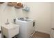 Functional laundry room includes a utility sink, washer, dryer, and upper storage shelves at 7547 Campus Cv, Sarasota, FL 34243