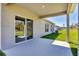 Covered back patio with sliding door and view of the green lawn and lush landscaping at 818 170Th E Ct, Bradenton, FL 34212