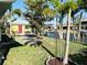 Well-manicured backyard with tropical trees, waterfront views, and a quaint yellow cottage at 9031 Hilolo Ln, Venice, FL 34293