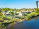 Waterfront view of the well-manicured property, with palm trees and a charming, colorful home at 9031 Hilolo Ln, Venice, FL 34293