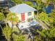 Charming cottage with metal roof, red door, and a cozy outdoor seating area, surrounded by lush greenery at 9031 Hilolo Ln, Venice, FL 34293