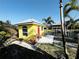 Charming waterfront property with a bright yellow exterior, red door, and relaxing patio space at 9031 Hilolo Ln, Venice, FL 34293