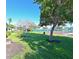 Grassy backyard with mature trees and a view of the community tennis courts at 9414 Andover Cir, Bradenton, FL 34210