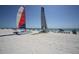 Beach view with sailboats, lounge chairs, and blue skies at 1001 Benjamin Franklin Dr # 511, Sarasota, FL 34236