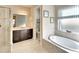Bright bathroom featuring double vanity, walk-in shower, and soaking tub beneath a window with striped shades at 1022 Overlook Ct, Bradenton, FL 34208
