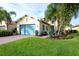 Charming yellow home with a turquoise garage door, lush landscaping and beautiful palm trees at 1022 Overlook Ct, Bradenton, FL 34208