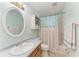 Stylish bathroom featuring an oval mirror, sink, toilet, tub/shower combo with curtain, and vanity storage at 1122 133Rd E St, Bradenton, FL 34212