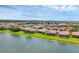 Expansive aerial shot showcasing tile-roofed homes along a scenic lake, with lush green landscapes and a clear blue sky at 1290 Cielo Ct, North Venice, FL 34275