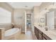 Bathroom featuring a soaking tub, tile flooring, dark vanity, and view into the bedroom with neutral walls at 1290 Cielo Ct, North Venice, FL 34275