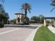 Elegant guard house at community entrance with lush landscaping, brick-paved road, and palm trees at 1290 Cielo Ct, North Venice, FL 34275