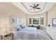 Bright main bedroom featuring a tray ceiling, ceiling fan, serene wall art, and tranquil views from the windows at 1290 Cielo Ct, North Venice, FL 34275