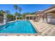 Community pool featuring plenty of lounge chairs, lush landscaping, and a covered seating area for relaxation at 1290 Cielo Ct, North Venice, FL 34275