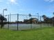 Fenced tennis court featuring well-maintained green surface with a gazebo nearby for relaxation between sets at 1290 Cielo Ct, North Venice, FL 34275