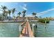 Wide view of a dock extending to a bayfront property with towering palms under a partly cloudy sky at 1325 Gulf Dr N # 247, Bradenton Beach, FL 34217