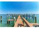 The end of the wooden dock has multiple boat mooring posts and multiple boat lifts on a clear blue ocean at 1325 Gulf Dr N # 247, Bradenton Beach, FL 34217