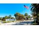 Perico Bay Club community entrance with an American flag, palm trees, and lush landscaping under a clear blue sky at 1389 Perico Point Cir # 140, Bradenton, FL 34209